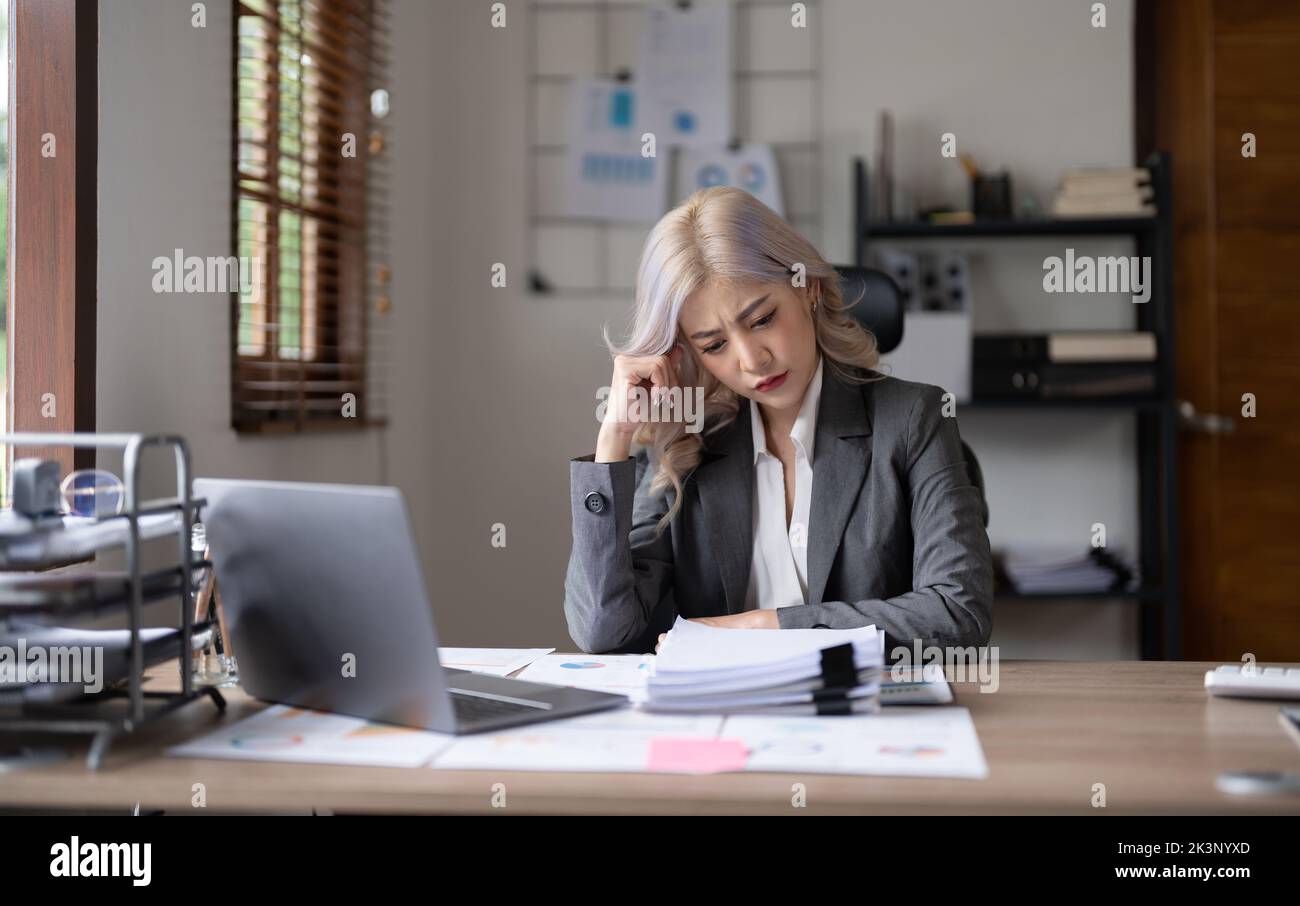 Bored Workaholic Accountant Employee With Headache. stressed working woman at business desk in a business office Stock Photo