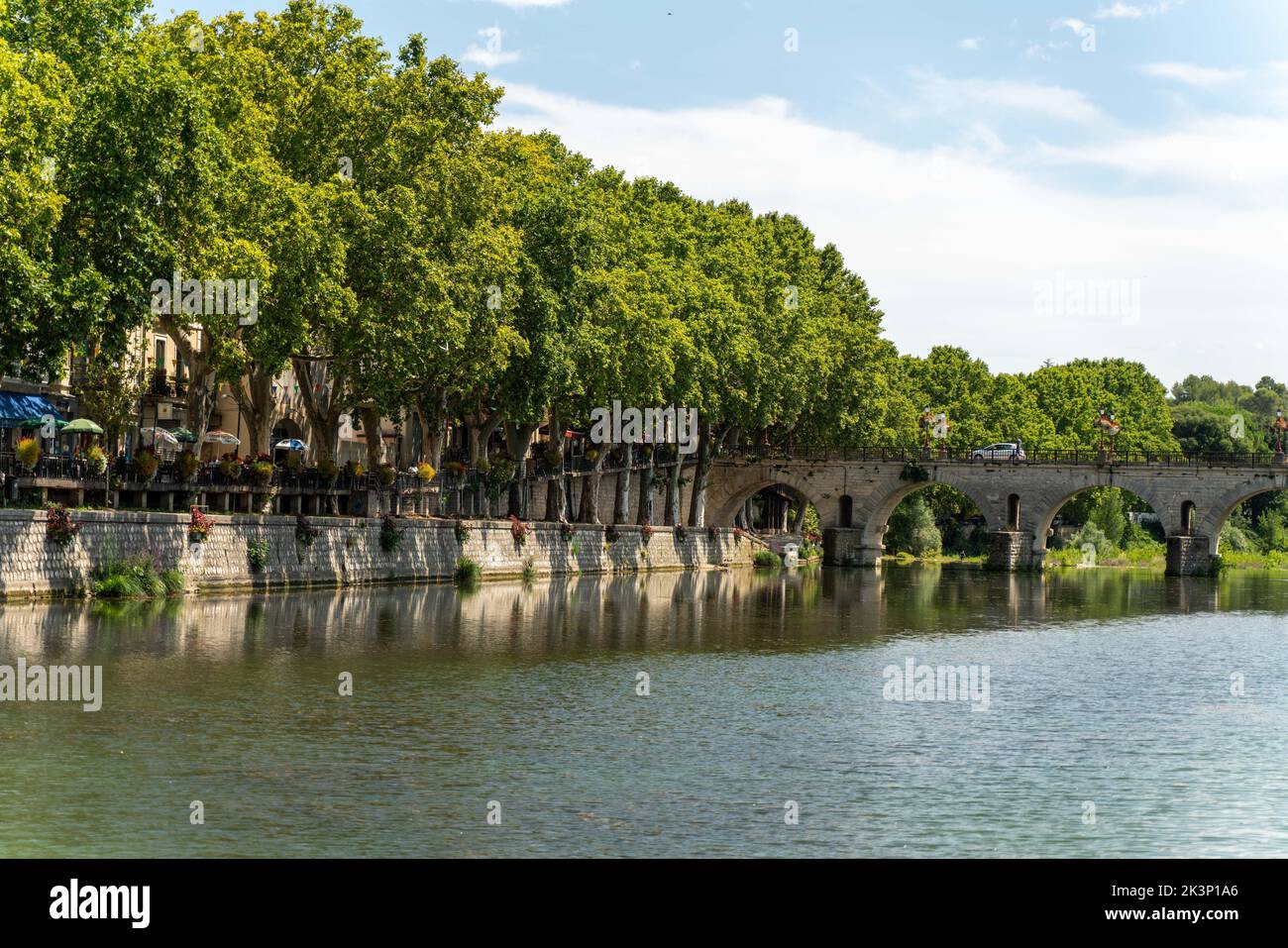 A beautiful view of a river surrounded by trees on a sunny day in Sommieres, Gard, France Stock Photo