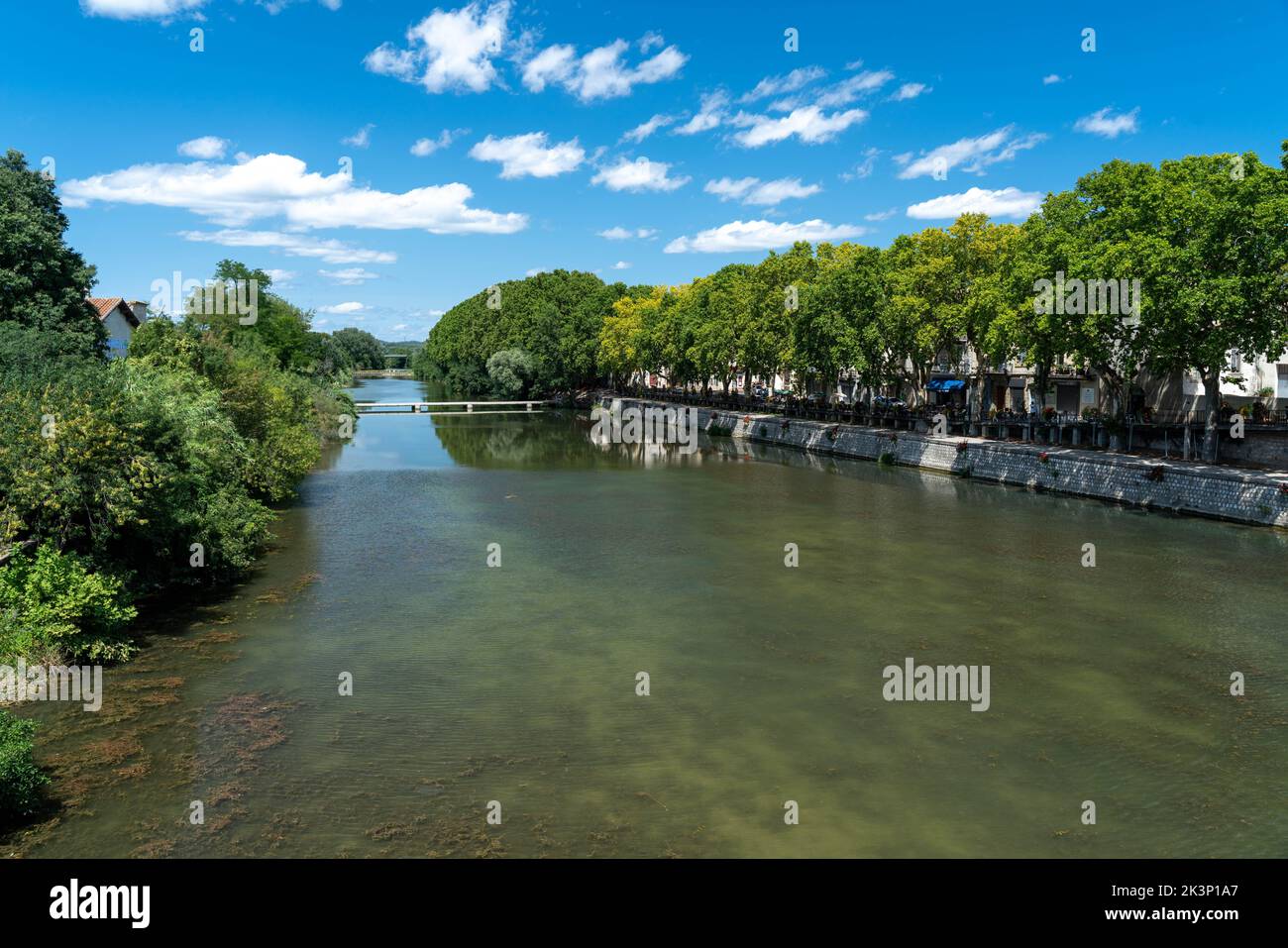 A beautiful view of a river surrounded by trees on a sunny day in Sommieres, Gard, France Stock Photo