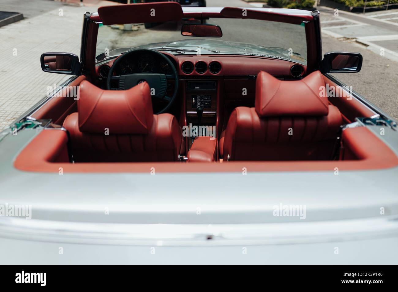 A vintage Mercedes Benz car with red seats and an open roof on the