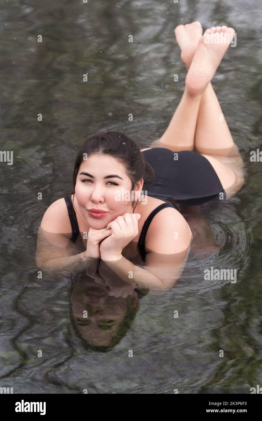 Overweight young woman in black onepiece bathing suit lying down