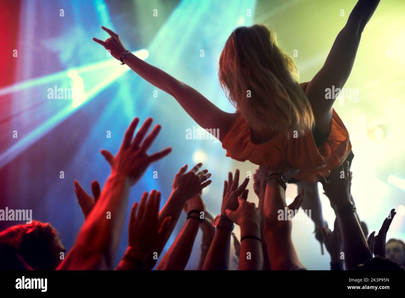 Crowd surfing. A young girl crowd surfing as a band plays one of her favourite songs. Stock Photo