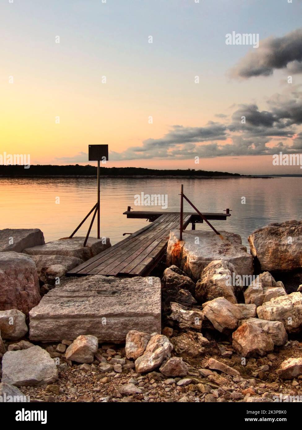 A vertical shot of a wooden pier on a rocky shore in the sunset Stock ...