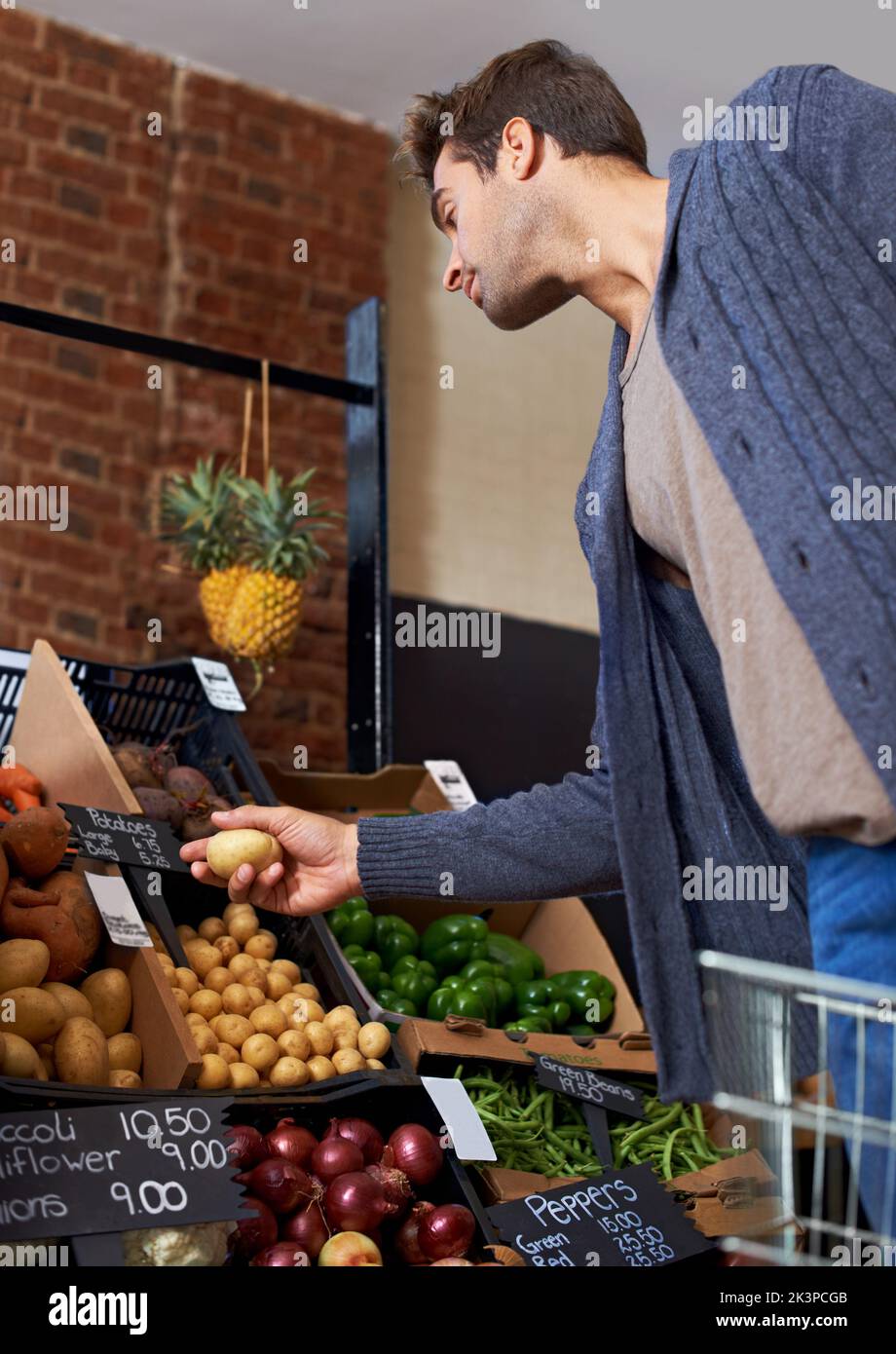 Choosing his produce carefully. a young man shopping for fresh