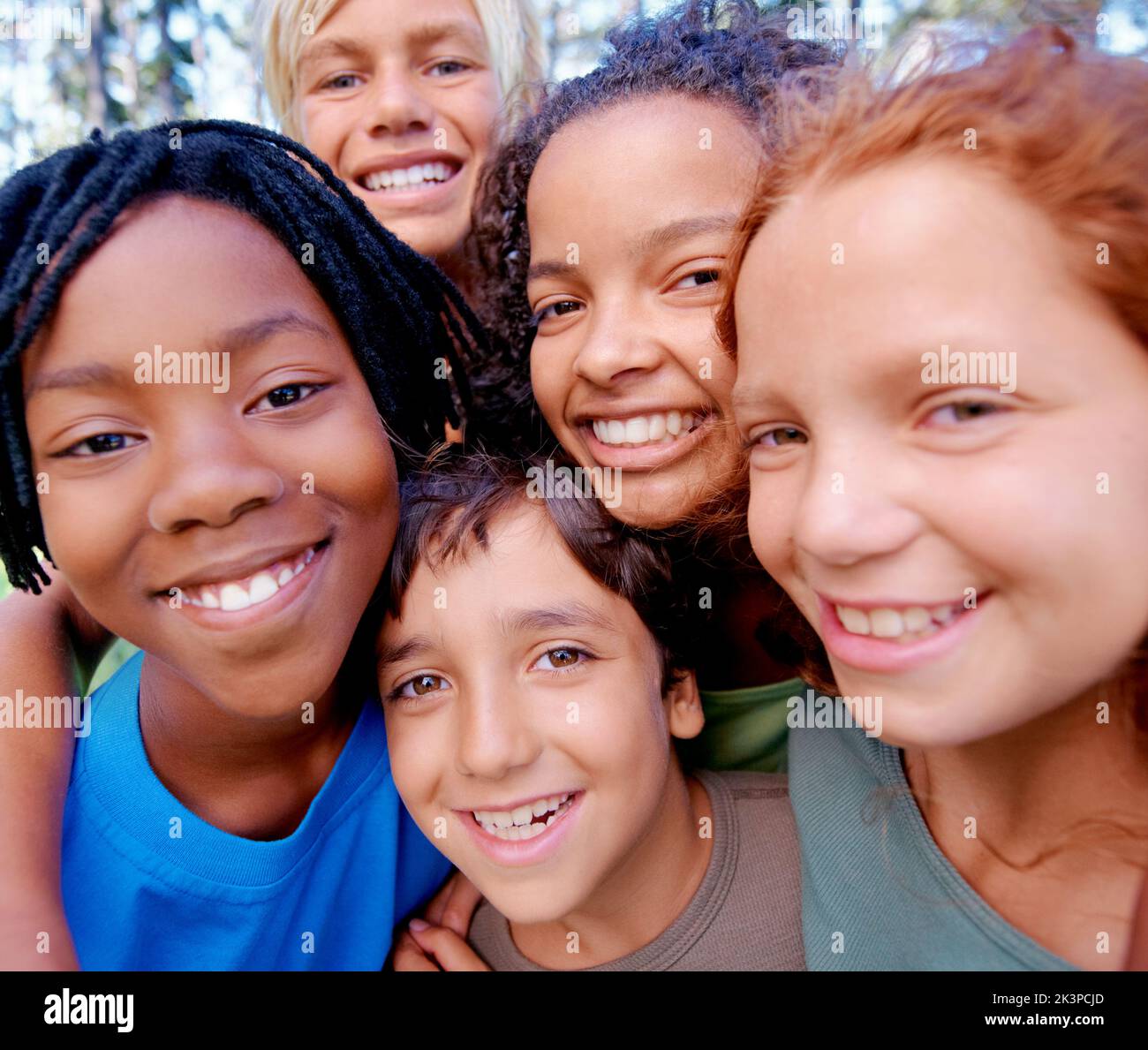 Friends are all you need. Closeup of a group of kids smiling at the camera while standing in the woods. Stock Photo