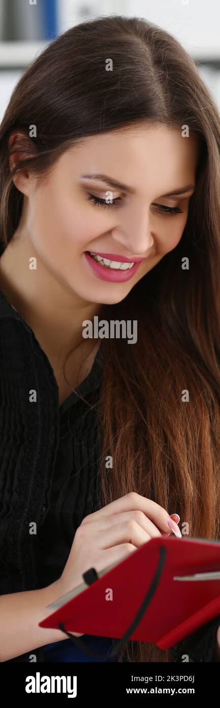 Woman holding silver pen ready to make note in opened notebook sheet ...