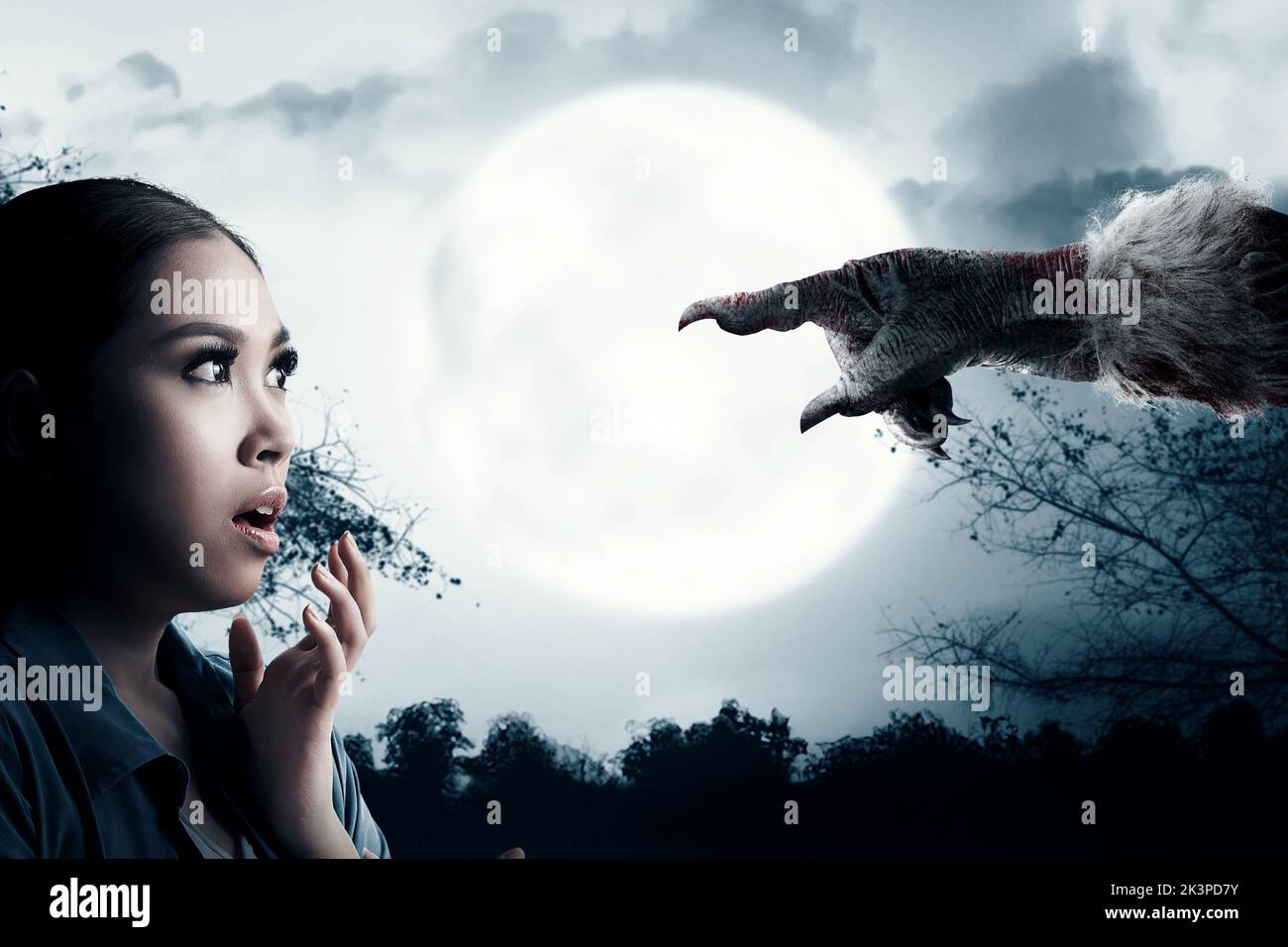 Asian woman scared looking at Werewolf hand with night scene background. Halloween concept Stock Photo