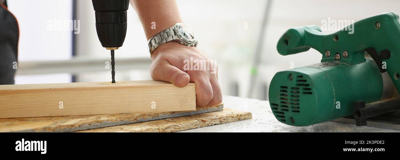 Workers instruments for repairing, man drill hole in wooden plank Stock Photo