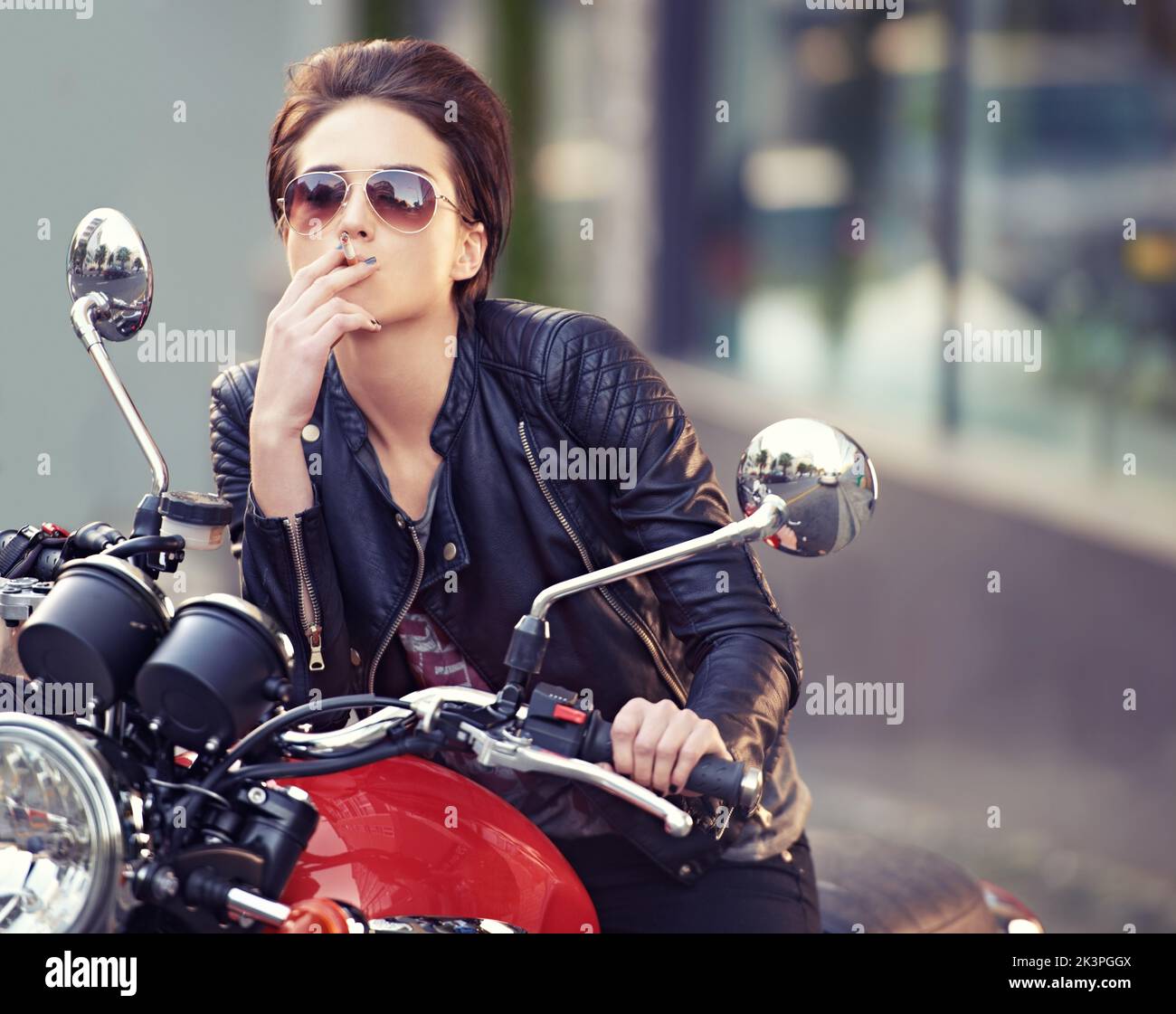 Dont mess with her. a young female biker smoking a cigarette Stock