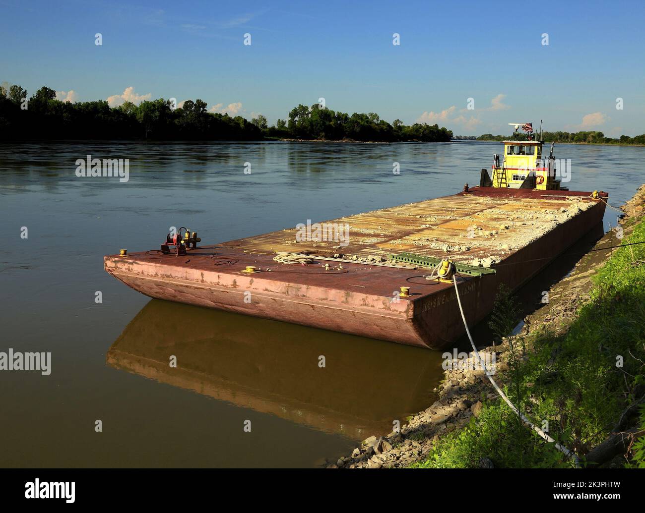A rusty old barge tied to the bank of the Missouri River Stock Photo
