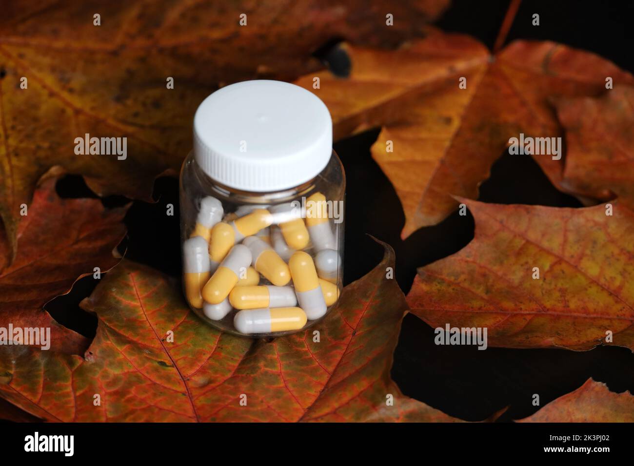 Pills on autumn maple leaves, bottle with capsules. Pharmacy, antidepressants, vitamins for immunity in flu season Stock Photo