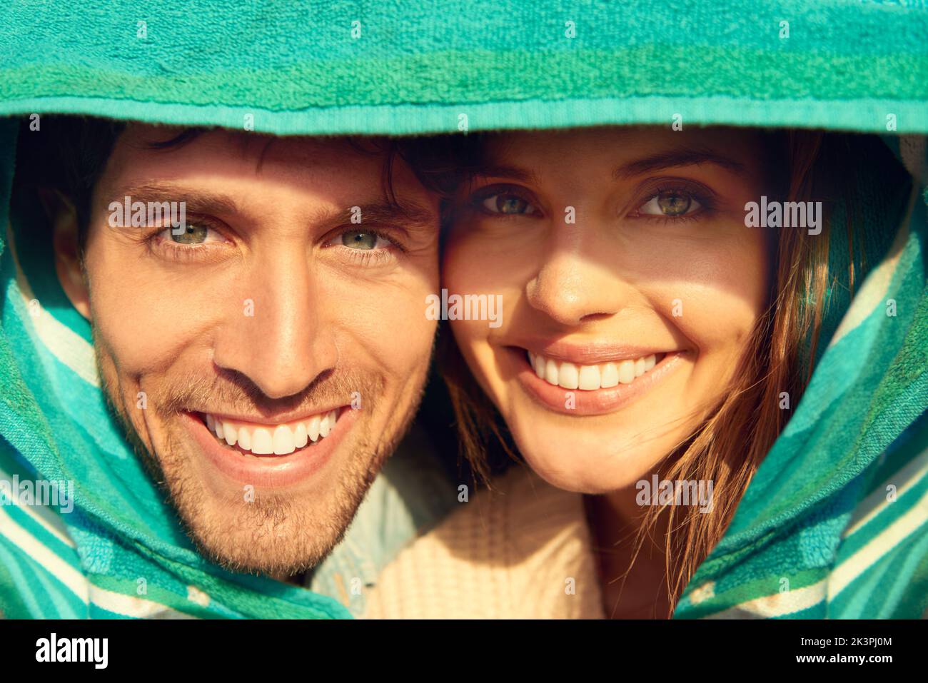 Sunshine cuddles. A loving couple covering their heads with a beach