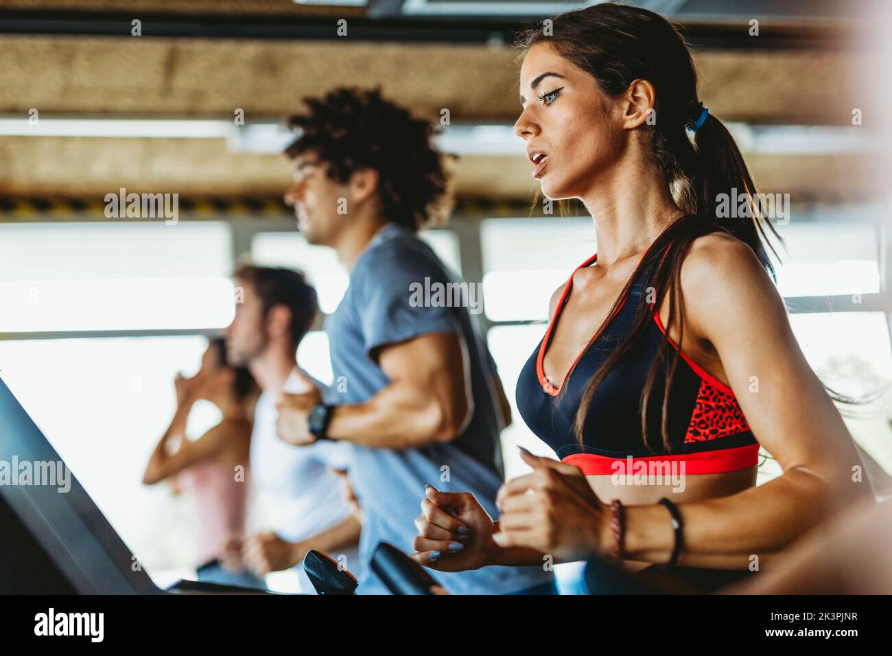 Group of fit young people running on a treadmill in health club. People sport concept Stock Photo