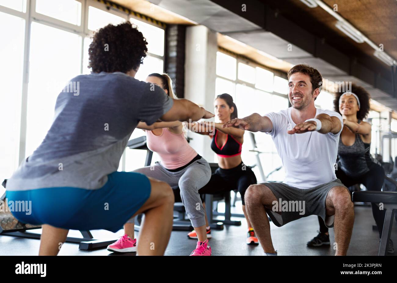 Group of young people, friends smiling and enjoy sport in gym. People exercise, work out concept. Stock Photo