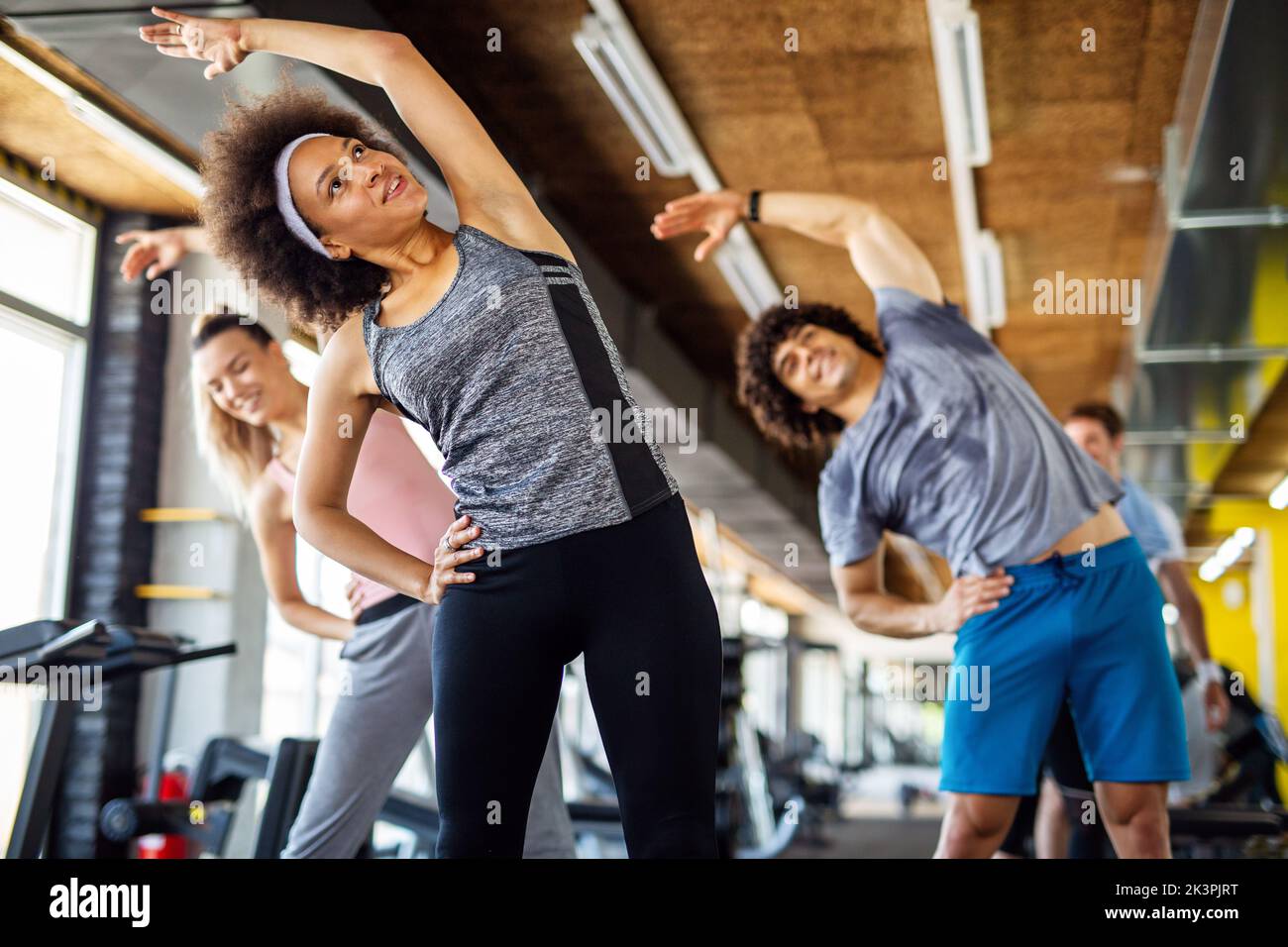 Multiethnic group of people training in a gym. Trainer and sportive fit persons exercising Stock Photo