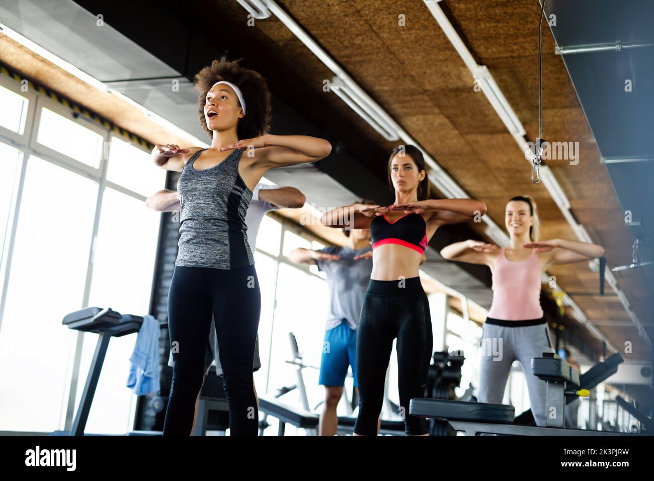 Multiethnic group of people training in a gym. Trainer and sportive fit persons exercising Stock Photo