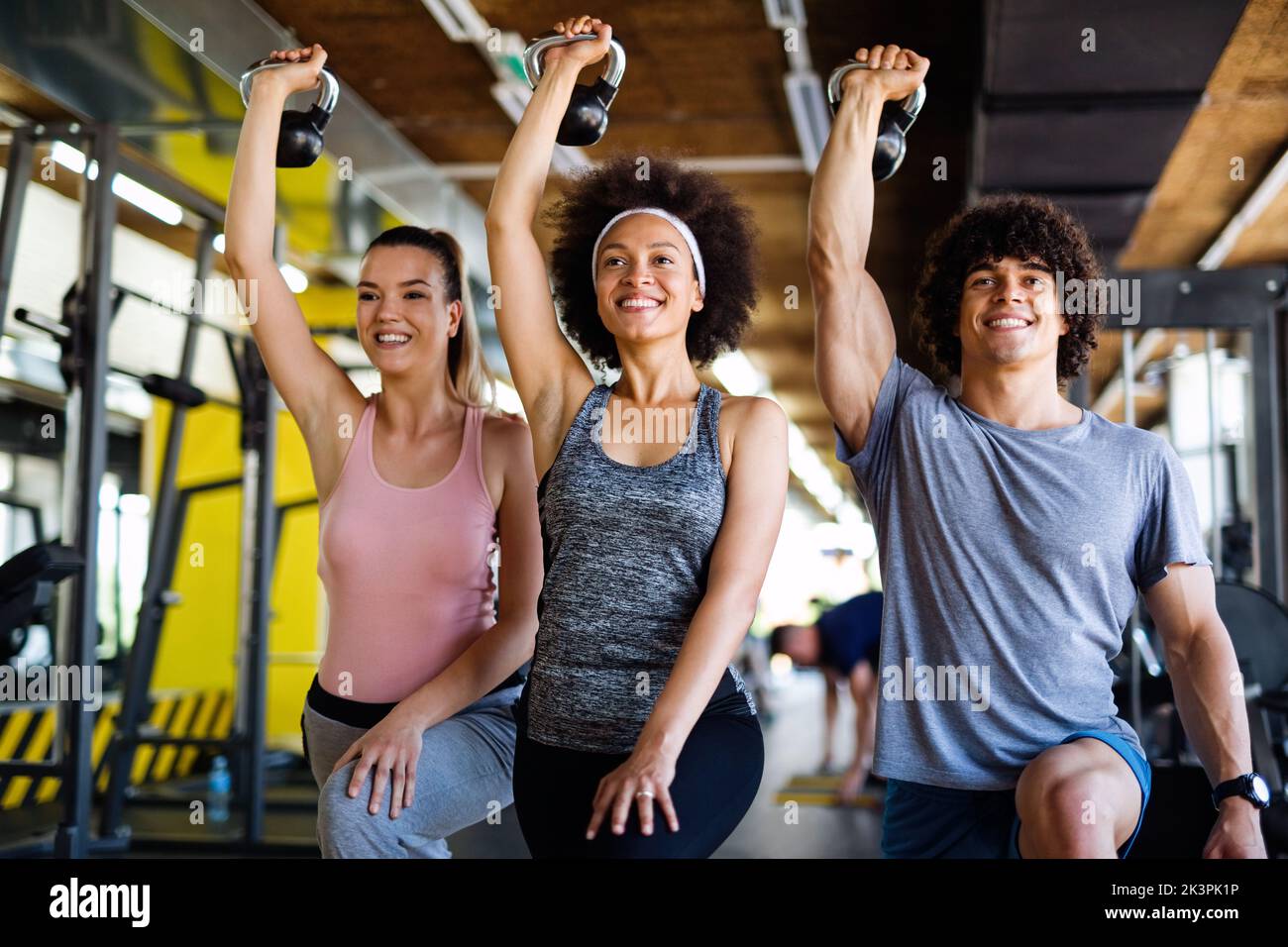 Group of fit people lifting dumbbells during an exercise class at the gym Stock Photo