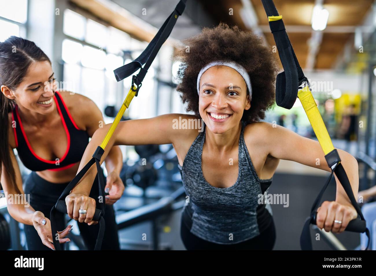 Beautiful woman doing exercises in gym with personal trainer together. Sport, people concept Stock Photo
