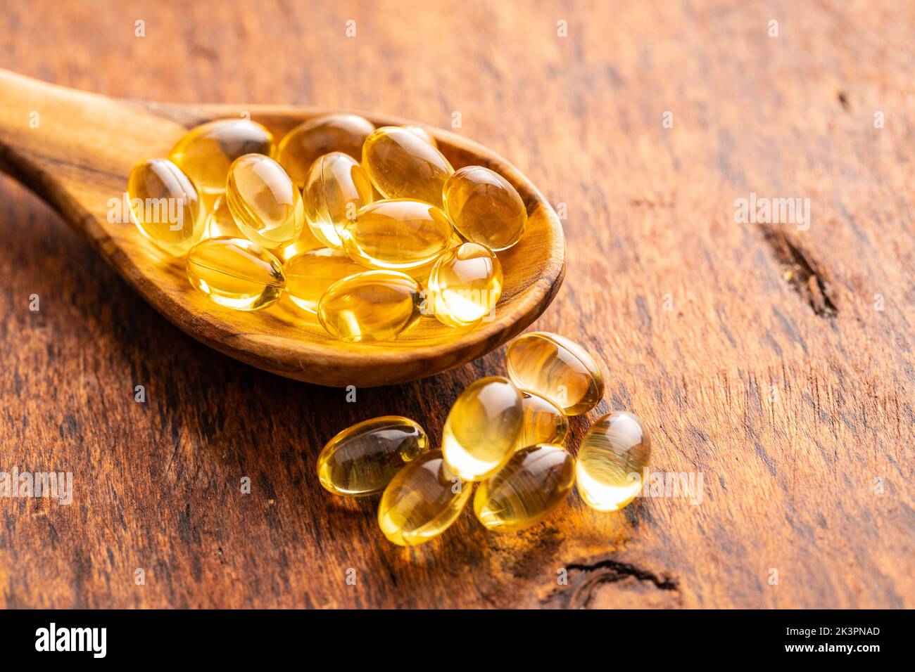 Fish oil capsules. Yellow omega 3 pills in spoon on the wooden table. Stock Photo