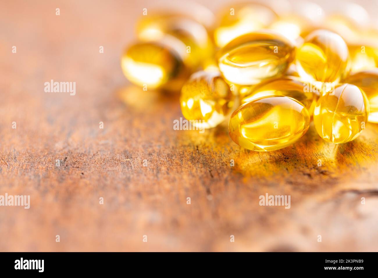 Fish oil capsules. Yellow omega 3 pills on the wooden table. Stock Photo