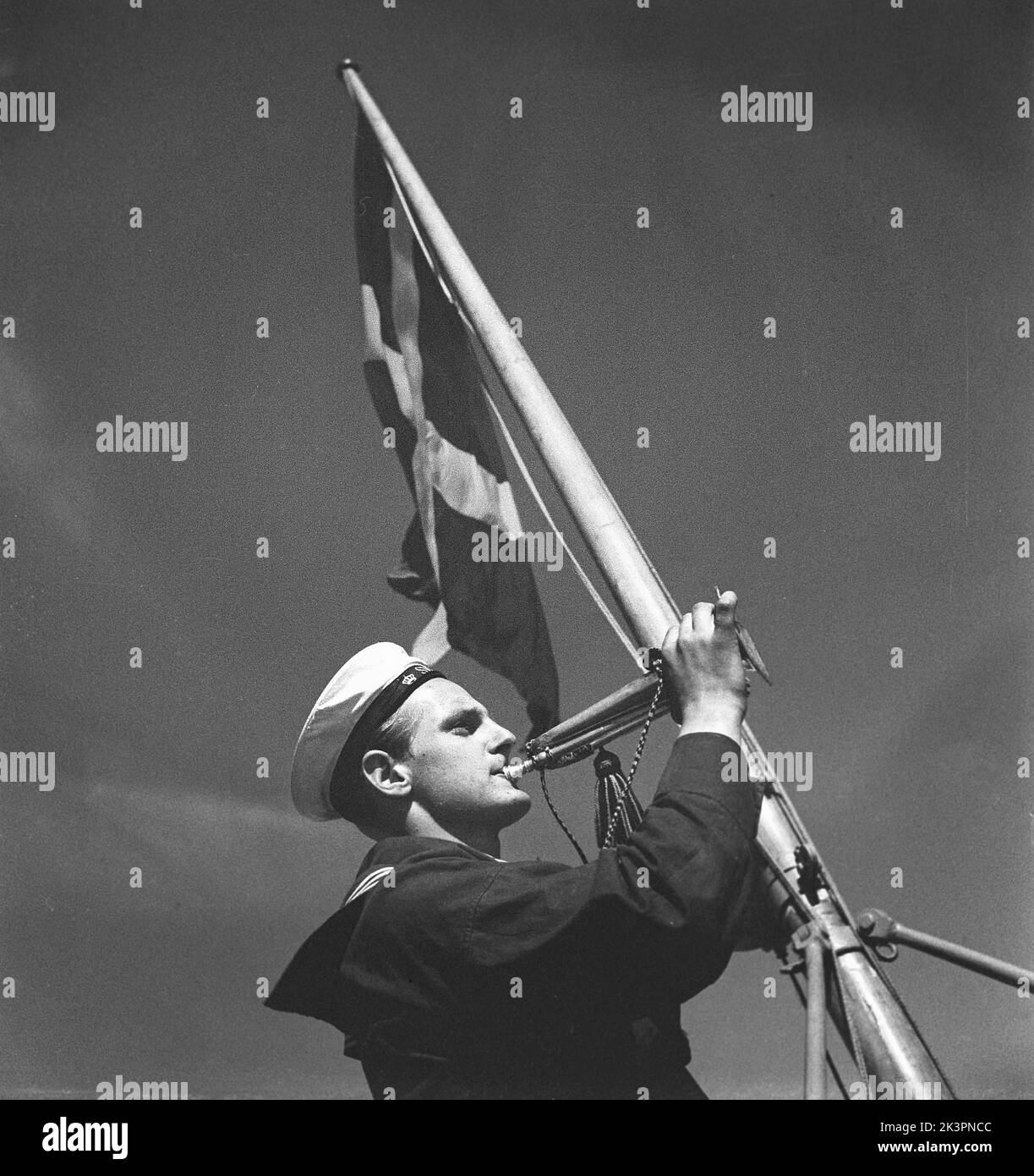 During World war II. The war ship Sverige during navy exercises at sea. Detail of a sailor signalling in his brass horn. Sweden june 1940. Kristoffersson ref 141 Stock Photo