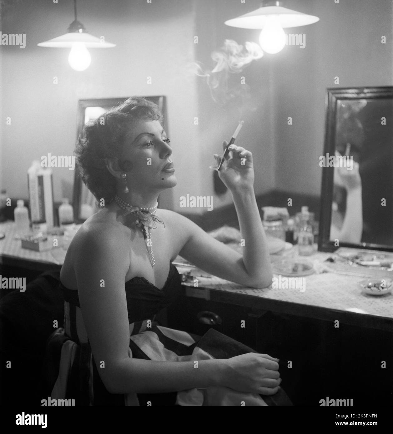 At the theatre in the 1950s. Actress dancer Karin Maria Elisabet Matisen, known as Topsy. A beautiful picture of her in her dressingroom behind the scenes where she looks glamourous smoking a cigarette.  Sweden 1952 Kristoffersson ref BH99-6 Stock Photo