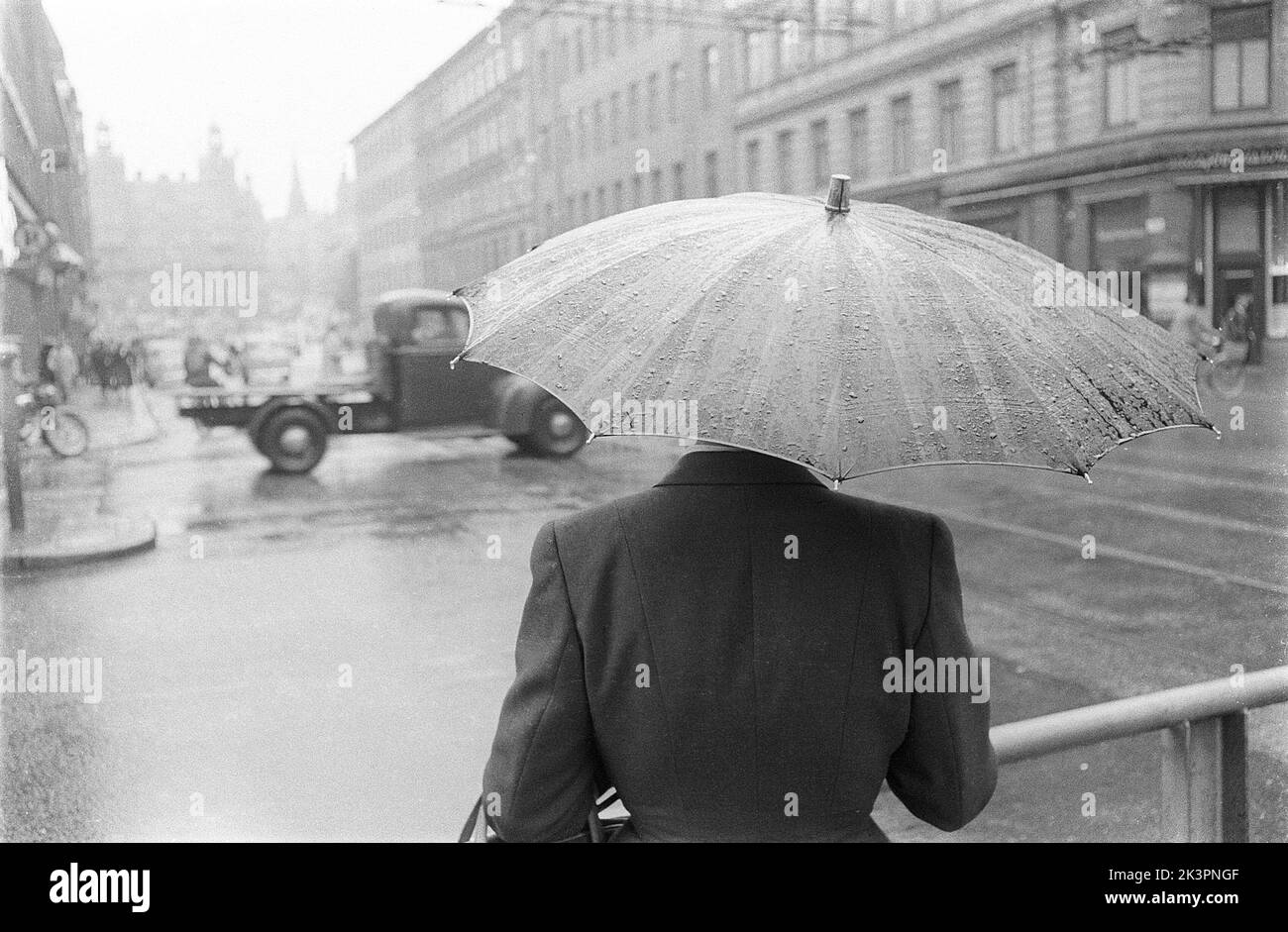 Umbrellas in the 1950s. The rain is pouring and a woman is seen holding an umbrella over herself. It's a rainy day in Stockholm Sweden 1953. ref 2A-1 Stock Photo