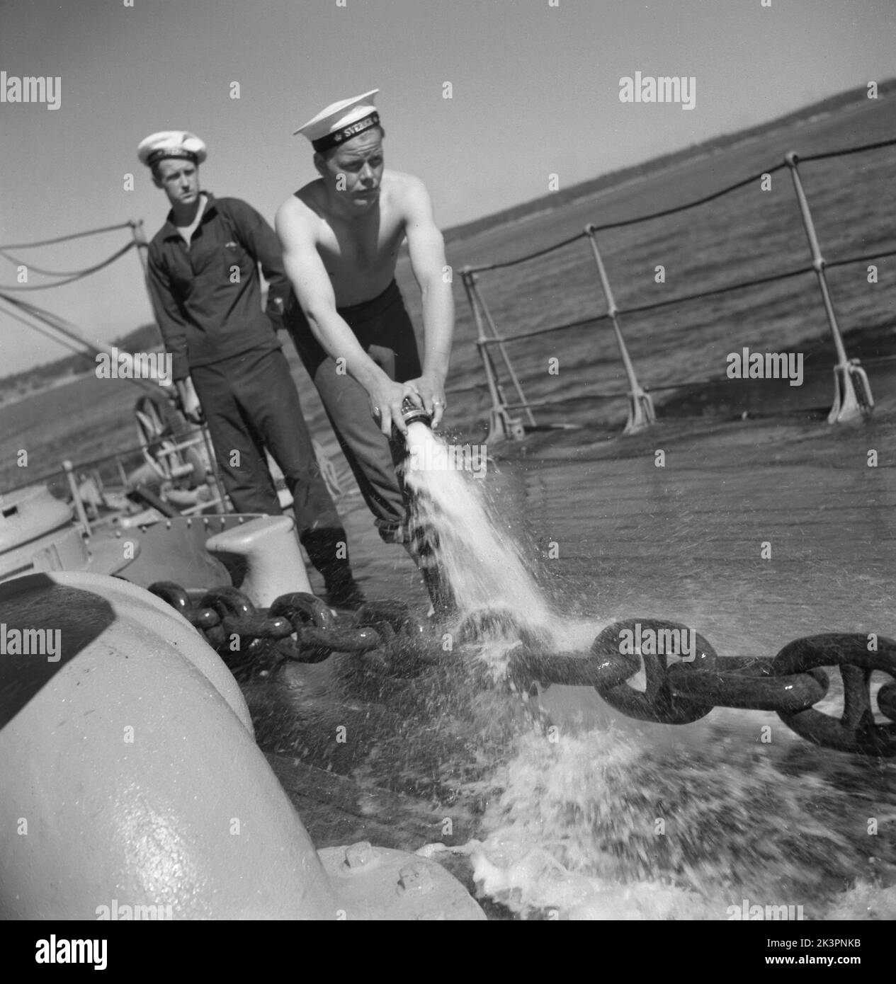 During World war II. The war ship Sverige during navy exercises at sea. The anchor chain is being pulled up and a sailor is hosing it with water to remove clay and mud from it.  Sweden june 1940. Kristoffersson ref 141 Stock Photo