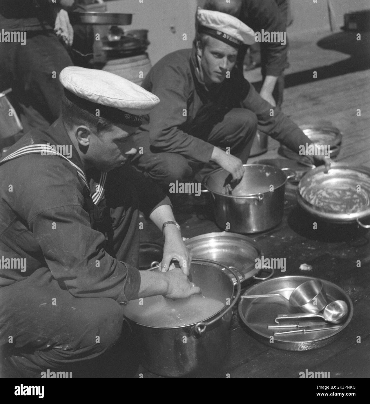 During World war II. The war ship Sverige during navy exercises at sea. Two sailors are seen cleaning the pots and pans on deck. Sweden june 1940. Kristoffersson ref 141 Stock Photo