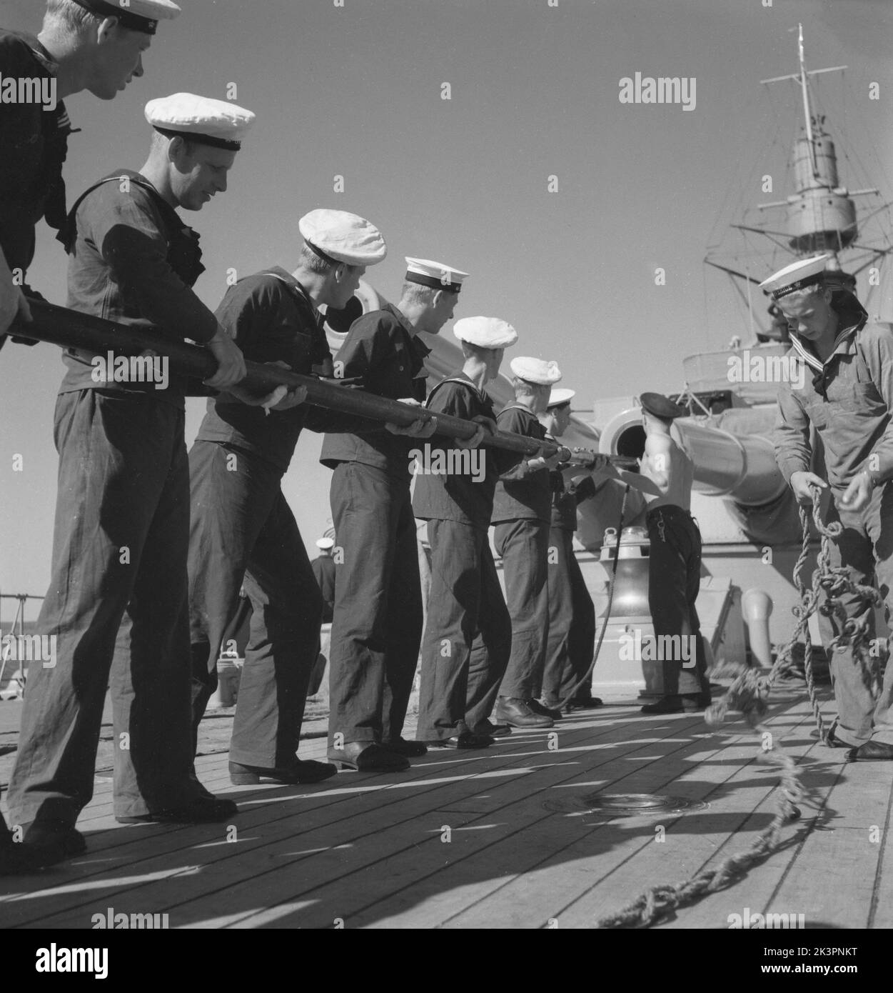 During World war II. The war ship Sverige during navy exercises at sea. The sailors are cleaning the cannon's inside pipe with a pole that on the end has something oiled that greases and cleans the cylindric pipe. Sweden june 1940. Kristoffersson ref 141 Stock Photo