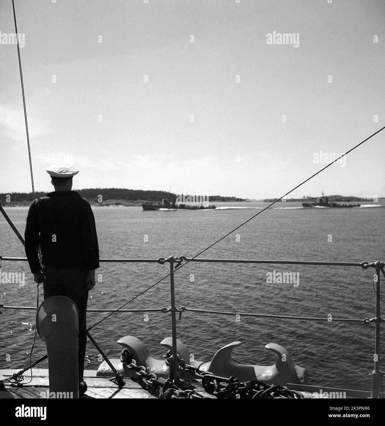 During World war II. The war ship Sverige during navy exercises at sea. Detail of a sailor standing in attention on deck with his eyes on two other swedish warships cruising on the side. Sweden june 1940. Kristoffersson ref 141 Stock Photo