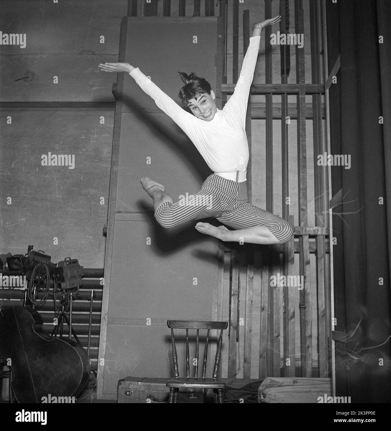 In the 1950s. An unknown young woman is pictured in the moment when being highest in the air having jumped off the chair. Besides the height of the jump she even manages to smile, keep eyecontact with the photographer and position her arms and legs in an artistic pose.  Sweden 1954 Kristoffersson ref BX38-7 Stock Photo