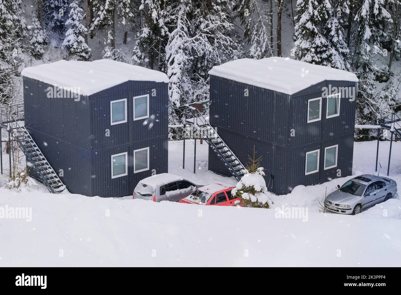 Modular houses in winter in the mountains. Tourist complex. Modern cottages in pine forest in winter. Stock Photo
