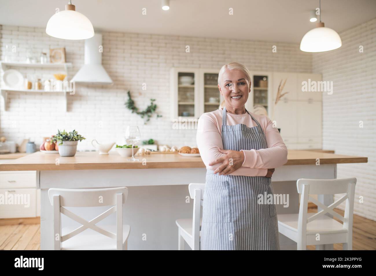 Cheerful mature housewife standing in the kitchen Stock Photo