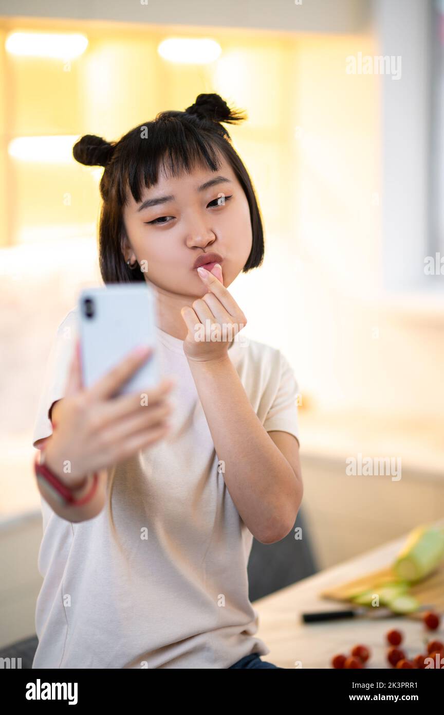 Cute girl photographing herself on the kitchen counter table Stock Photo