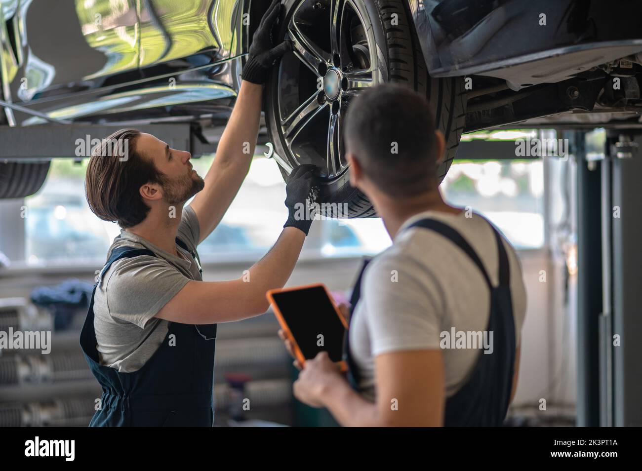 Two car repair shop workers fixing the client vehicle Stock Photo