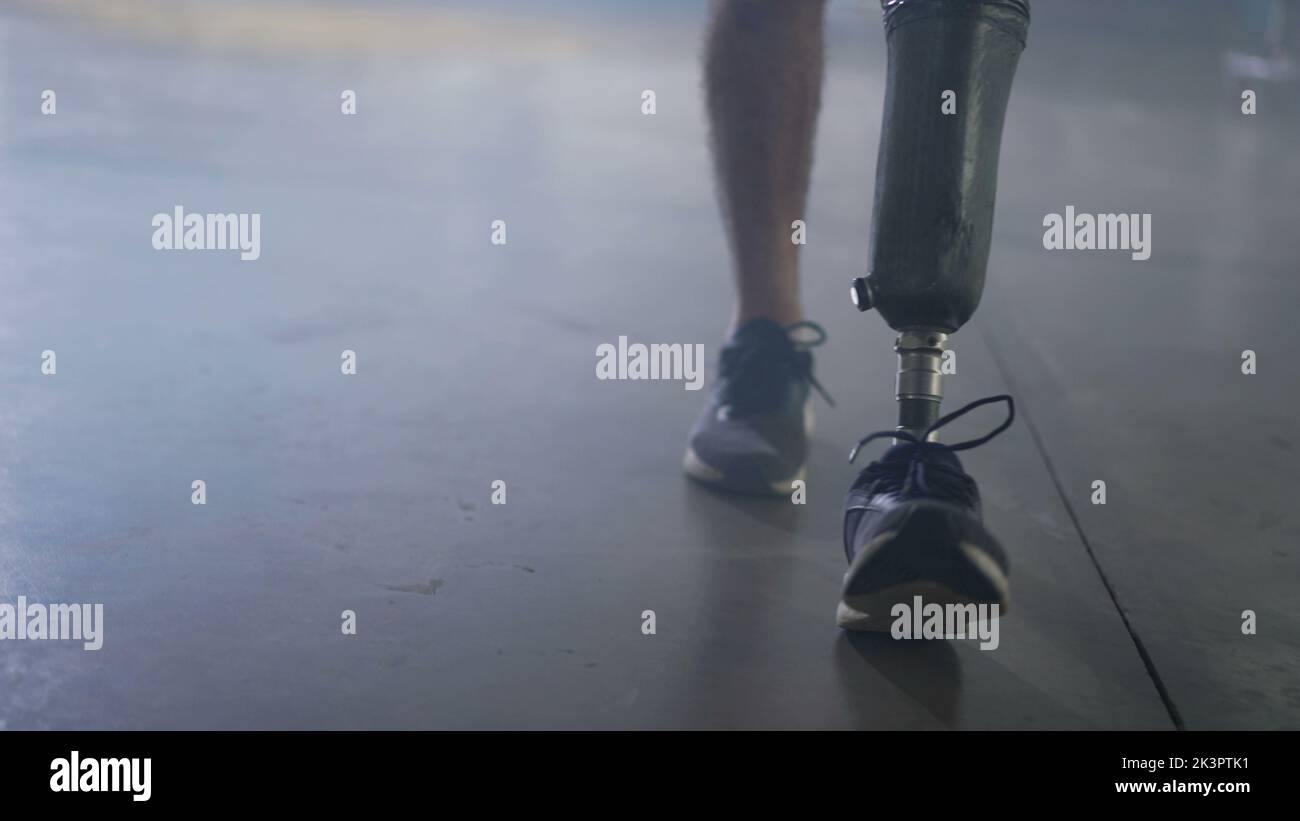 Disable Leg Disabled person walking with his prosthetic leg indoors. Amputee man ...