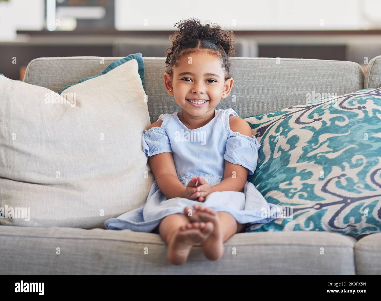 Children, girl and happy with a cute female kid on a sofa in the living room of her home alone. Kids, cute and smile with a portrait of an adorable Stock Photo