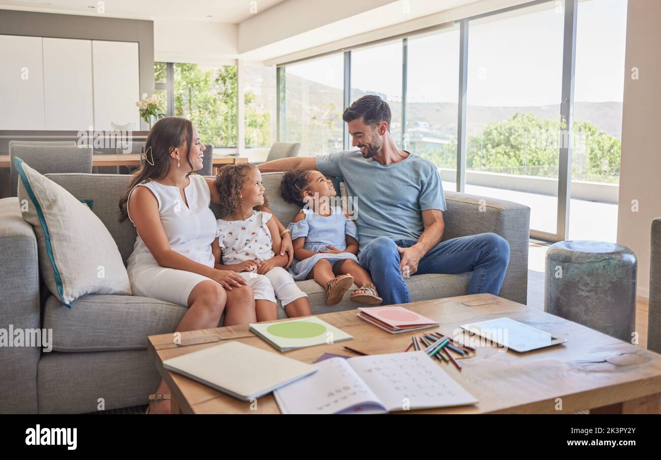 Happy family, children and parents talking on a sofa, relax and bonding in a living room at home. Love, quality time and affection by interracial Stock Photo