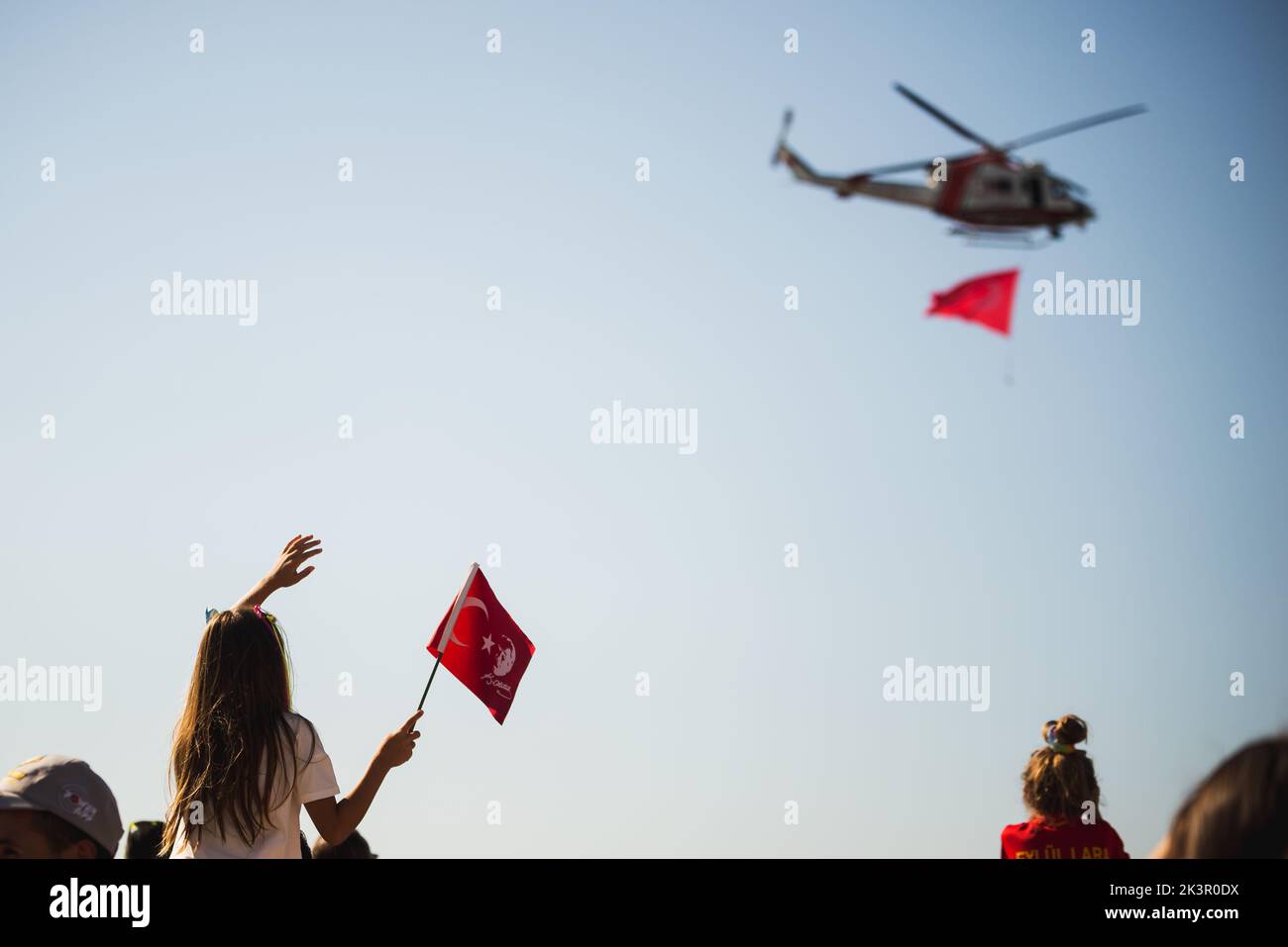 Izmir, Turkey - September 9, 2022: Close up shot of a Turkish flag which a girl holding in the crowded people with gendarme helicopter on the sky on t Stock Photo