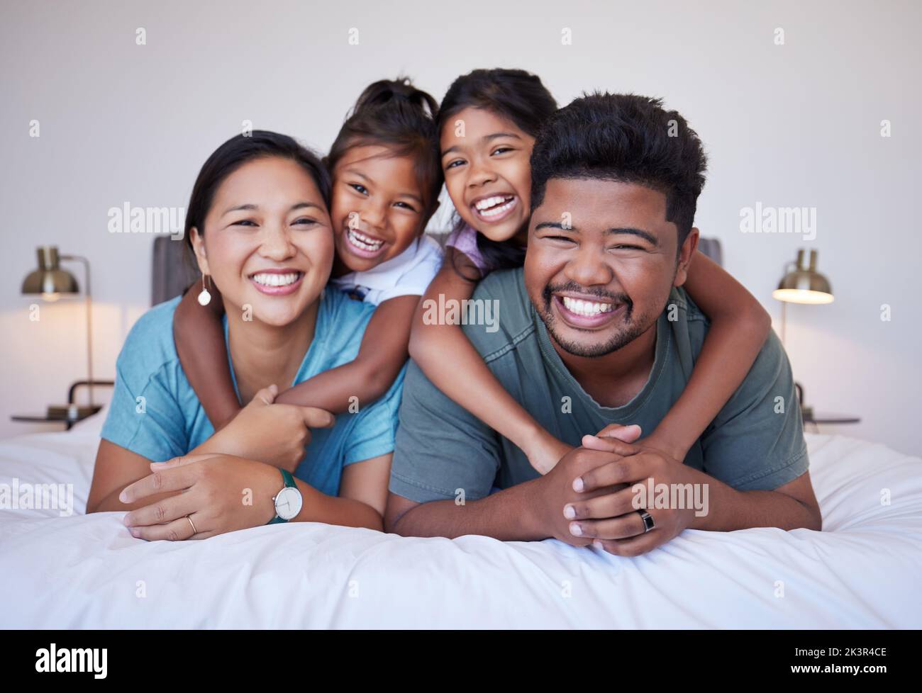 Portrait of a happy Asian family on the bed with a smile on their face. Multicultural Indian family in their bedroom smiling, laughing and having fun Stock Photo