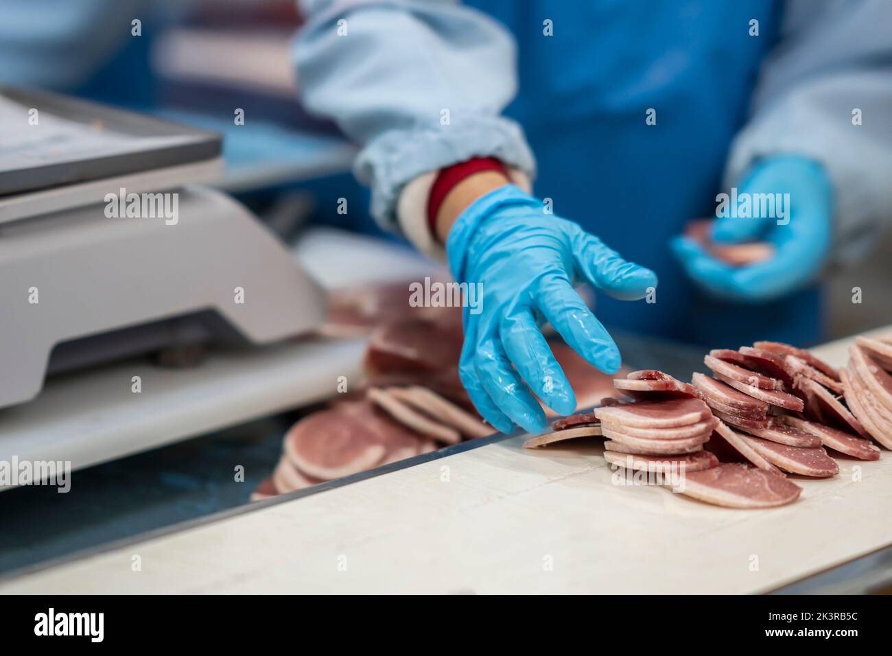 Mid section of butchers cutting meat and checking the weight of meat at