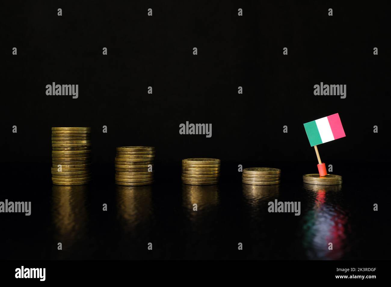 Italy economic recession, financial crisis and currency depreciation concept. Italian flag in decreasing stack of coins in dark black background. Stock Photo