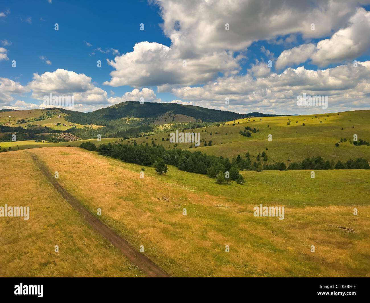 Beautiful white clouds are flowing across the sky over the green Zlatibor hills landscape on sunny summer day, popular serbian travel destination Stock Photo