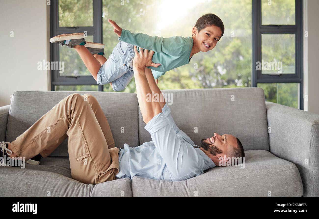 Children, family and love with a man and boy playing together on a sofa in the living room of their home. Father, son and kids with a male parent Stock Photo