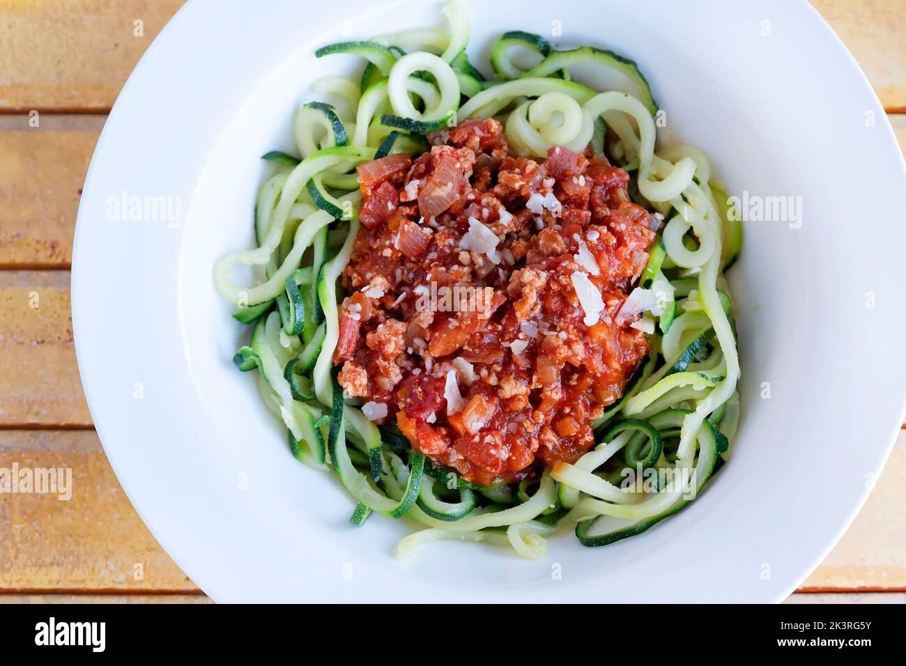 A bowl of ragu bolognaise served on a bed of spiralized courgette or zuchinni, known as courgetti. A low carb keto alternative to spaghetti Stock Photo