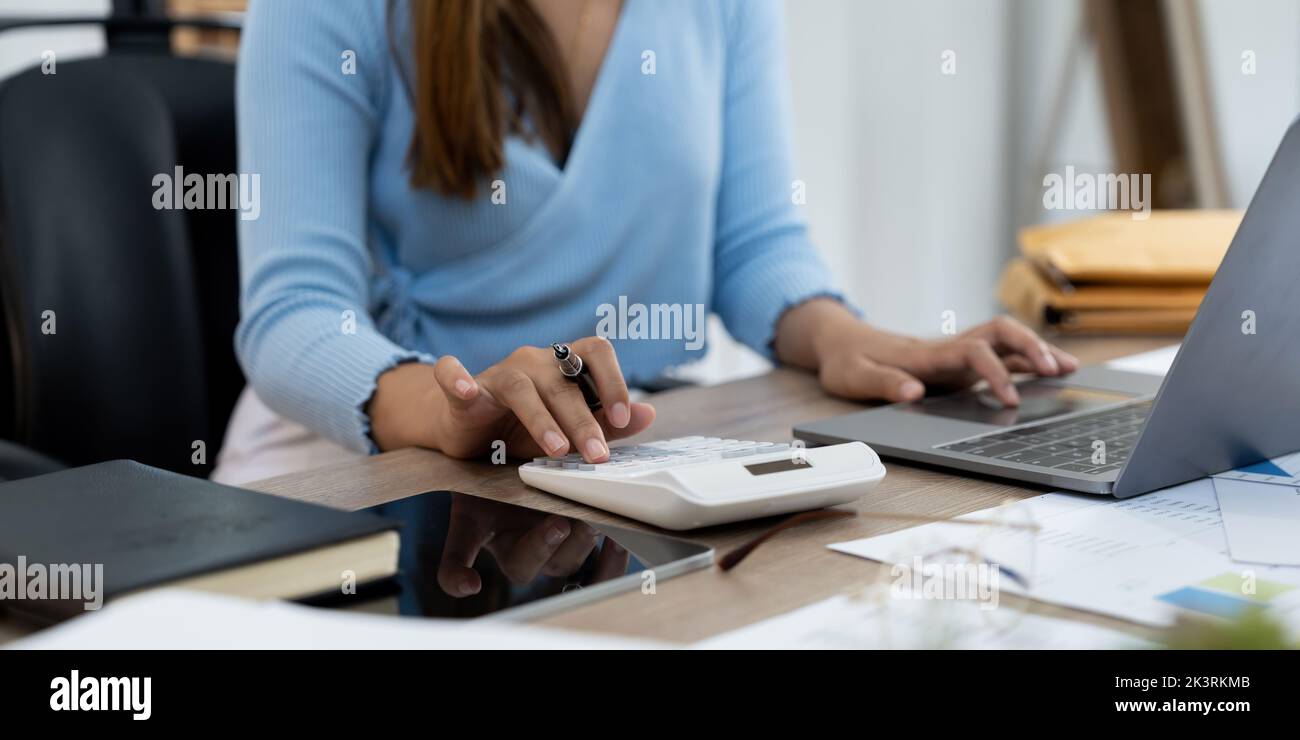Woman hand holding pen and using calculator with doing finance on desk at home office Stock Photo