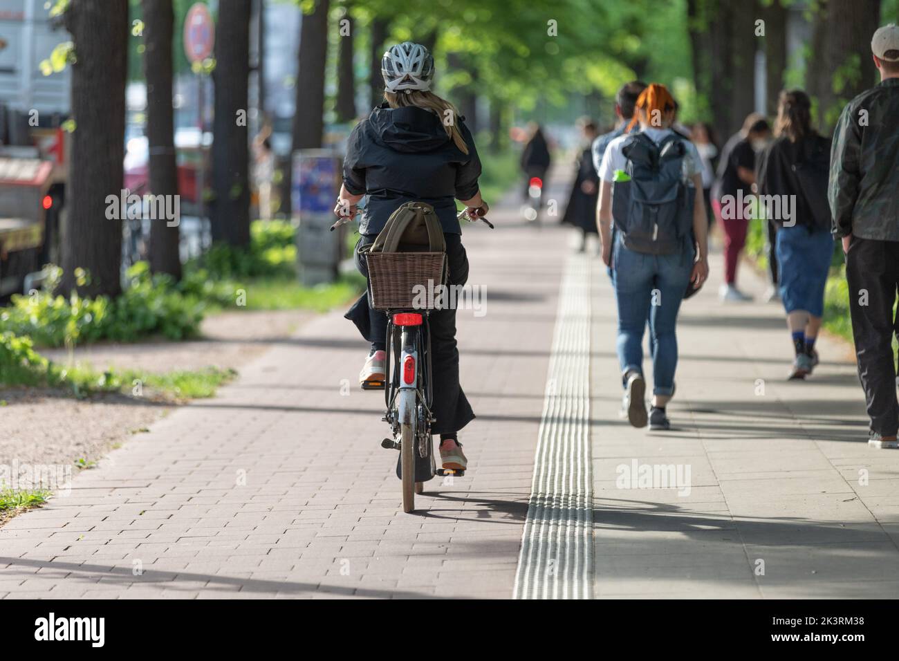 female cyclist with helmet on bicycle alley Stock Photo