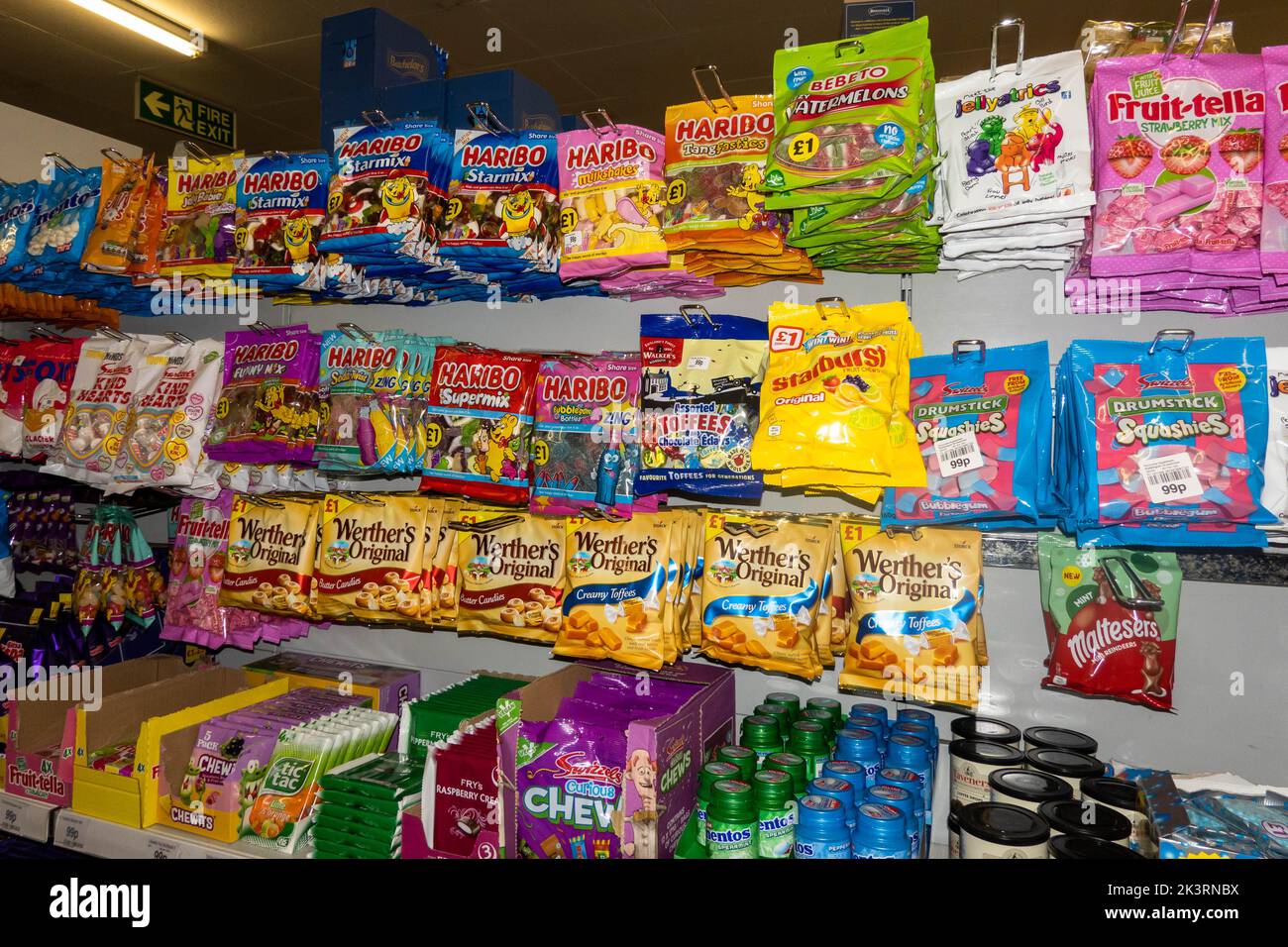 Bags of assorted sweets hanging from a supermarket shelf in England UK Stock Photo