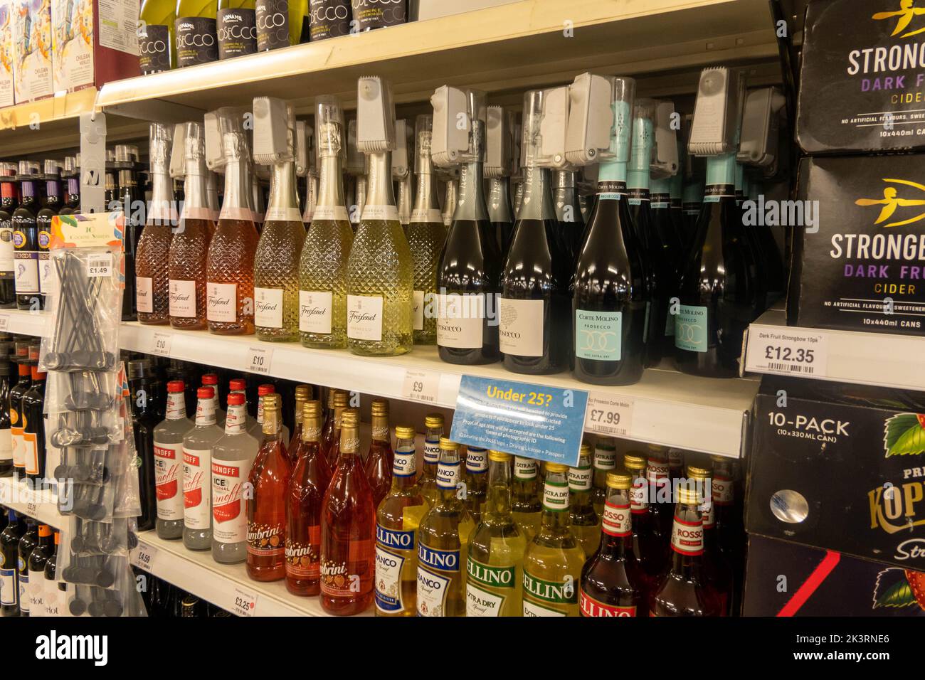 Bottles of wine and spirit on a shelf in a supermarket with security tags on each bottle to stop shop lifting in the UK Stock Photo
